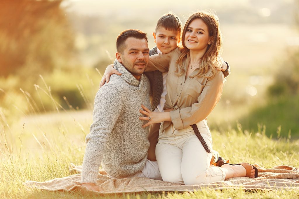 Family with cute little child. Father in a gray sweater. Sunset background.